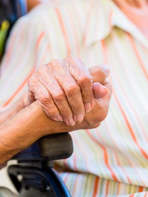 Nurse holding hand of senior woman in pension home.