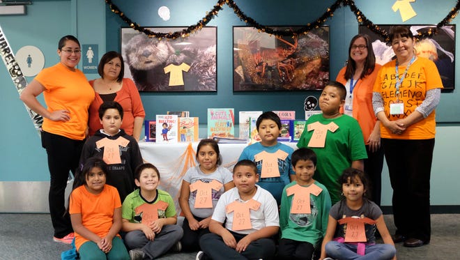 Clad in orange, César Chávez Library staff and some of the many kids in the homework center pose with anti-bullying books on Thursday, October 27th.