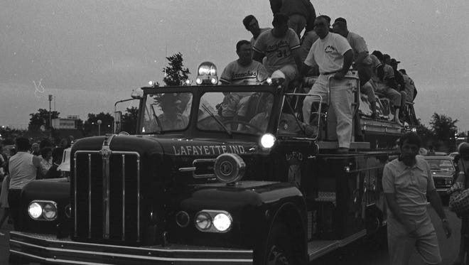 Lafayette Jefferson's state champion baseball squad prepares for a homecoming fire truck ride after capturing the IHSAA title in Indianapolis. Proud local fans cheered the team members Saturday evening during the traditional trip through the city's downtown and residential sections. In uniform at upper left is Paul "Spider" Fields, baseball coach; next to him is Joe Heath (No. 31), assistant coach; and Harold Cordell (in white). Photo taken June 25, 1973,