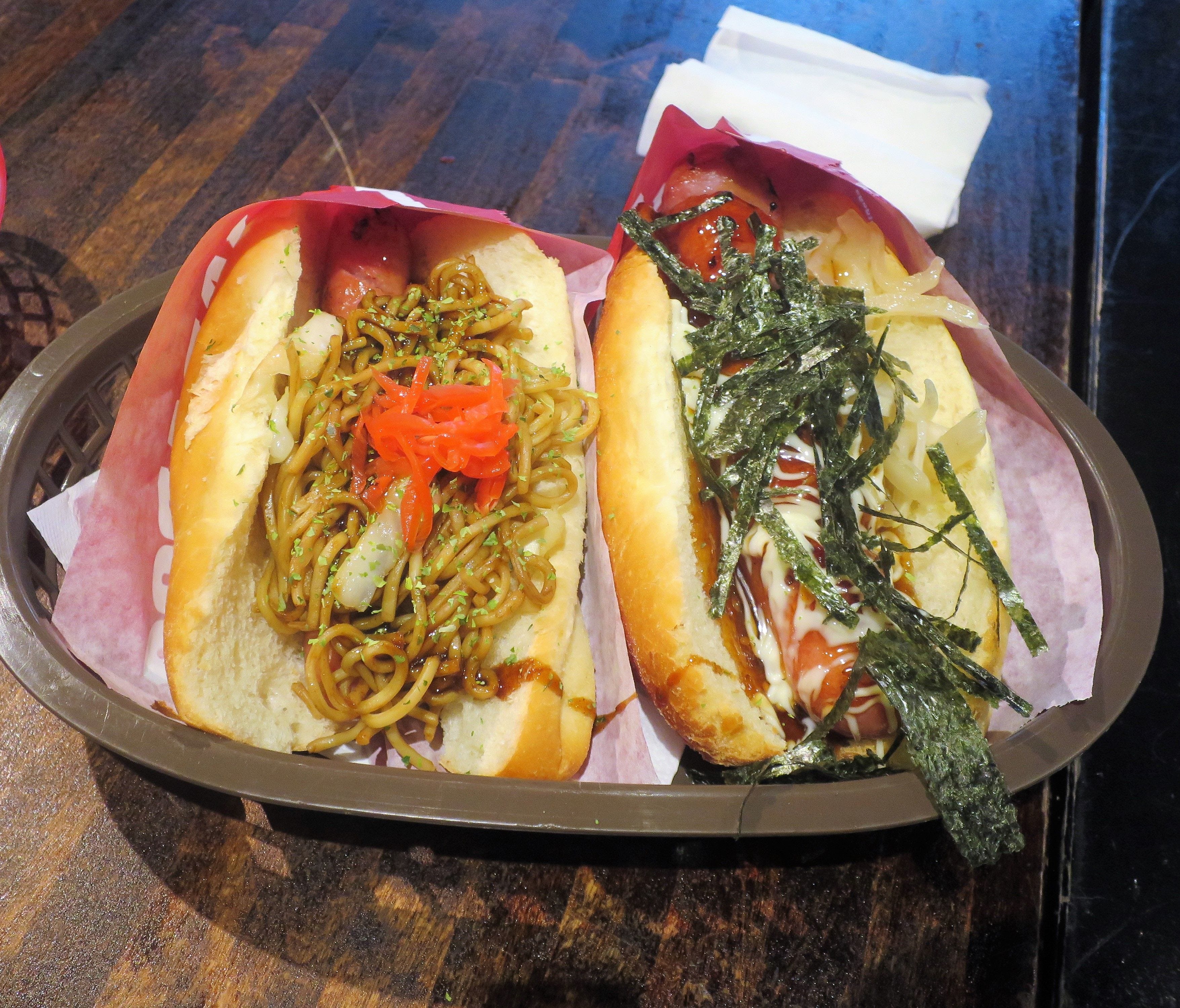 The Arabiki pork hot dog topped with yakisoba noodles (left) and the bestseller, the Kurobuta Terimayo (right), are two popular Japadog specialties.
