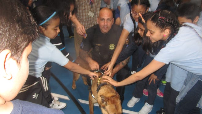 Paterson police Sgt. Ryan Curving and his K-9 partner surrounded by students at School 24's Career Day.
