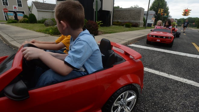 Toy cars are driven through the Kiwanis Safety Village during a past Safety Kamp as campers learn how to obey traffic signals and stop signs.