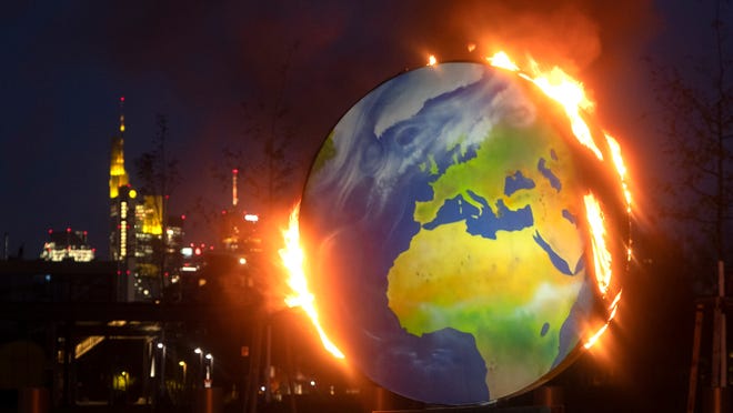 A makeshift globe burns in front of the European Central Bank in Frankfurt, Germany, Wednesday, Oct. 21, 2020. Activists of the so-called "KoalaKollektiv", an organization asking for climate justice, protested with the burning of the globe against the ECB's climate policy.