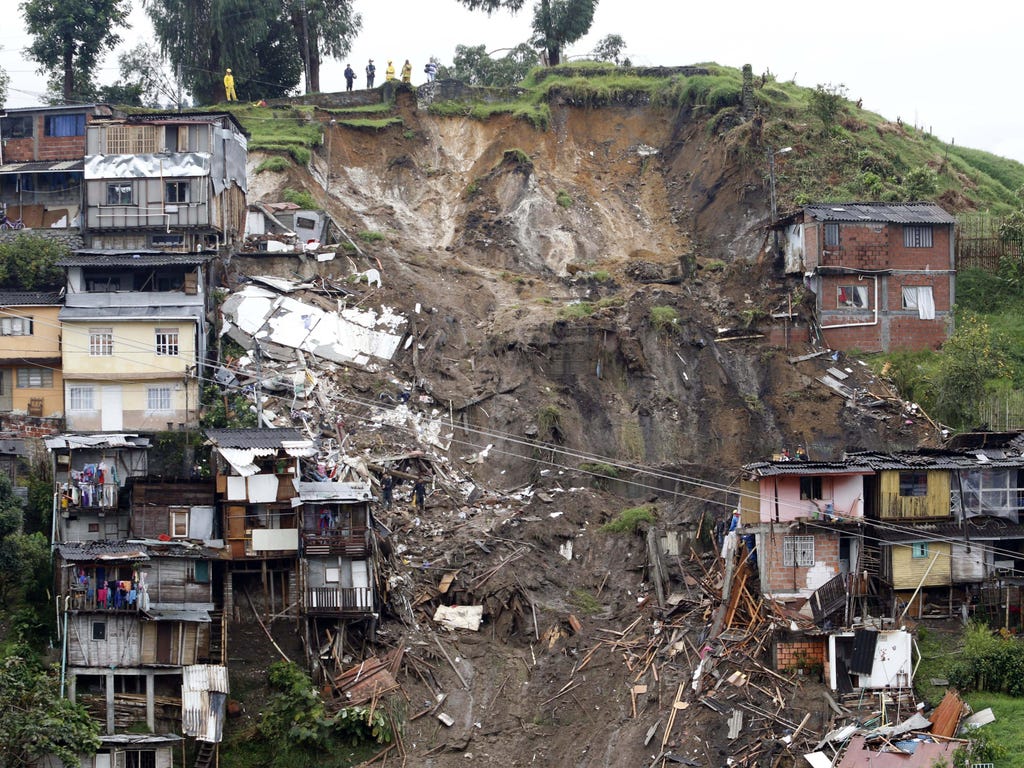 Rescue workers survey an area where a landslide destroyed several homes in Manizales, Caldas, Colombia. At least 11 people were killed and 20 are missing after heavy rains caused landslides in this mountainous region of Colombia.