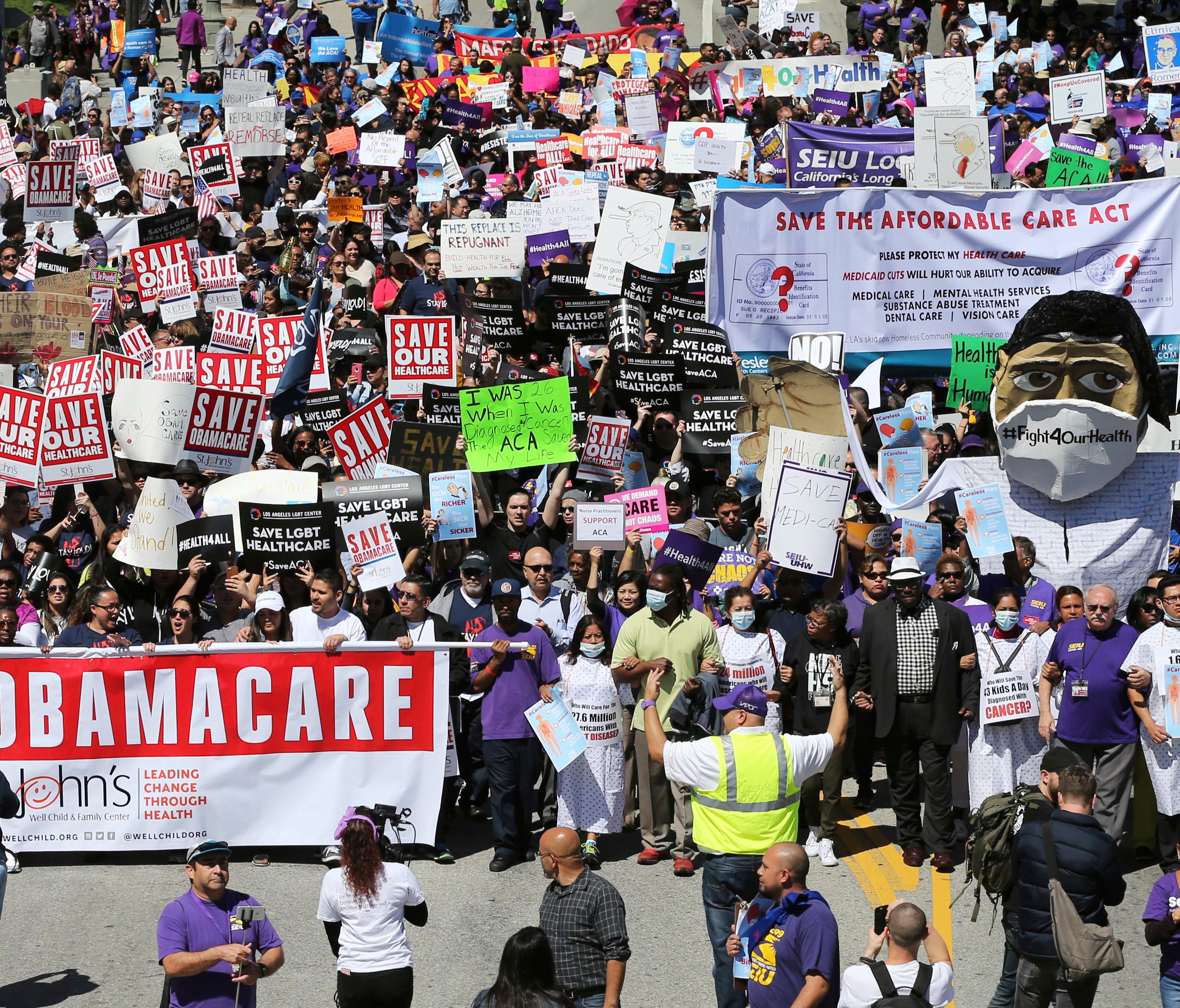 Hundreds of people march through downtown Los Angeles protesting President Trump's plan to dismantle the Affordable Care Act, also known as Obamacare, on  Thursday.