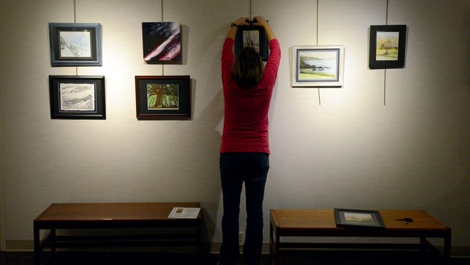 Lancaster High School art teacher Shannon Fish hangs some of her artwork Tuesday afternoon, Jan. 23, 2018, at the Fairfield County District Library in downtown Lancaster. Current and former Lancaster City Schools art teachers are displaying their work on the library's third floor beginning Sunday.