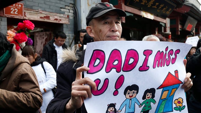 A relative holds a sign reading 'Dad I miss U!', outside the Yonghegong Lama Temple in Beijing.