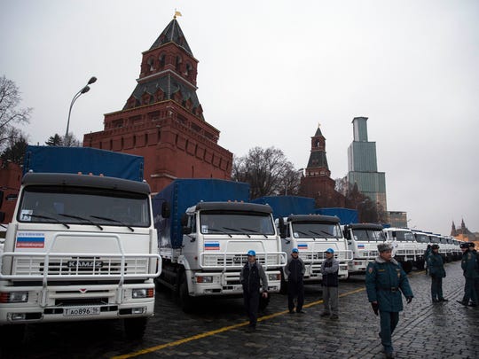 Drivers and Russian Emergency Ministry officers stand near the Kamaz trucks presented to the UN World Food Program as a gift from Russia in Moscow, Russia, Tuesday, Dec. 16, 2014.