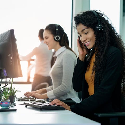 Smiling tech support workers wearing headsets at a