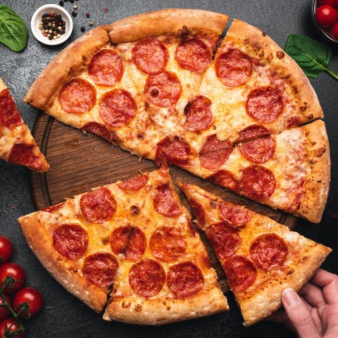 Pepperoni pizza cut into eight slices, with hand t