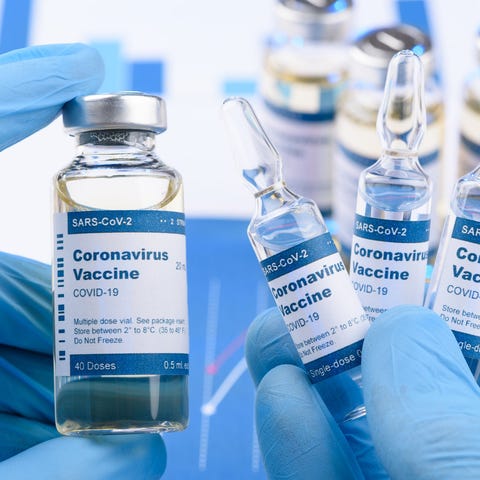 Gloved hands holding coronavirus vaccine bottles