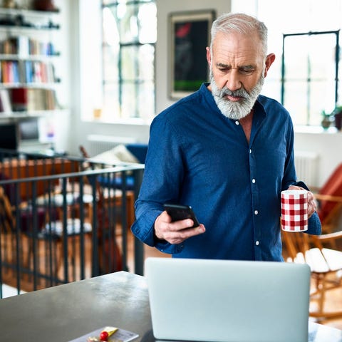 Person looking at laptop while holding phone and c