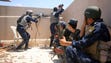Iraqi forces take a position on the roof of a building