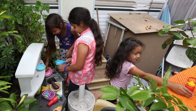 Scarlett Brito, 9, left, Allison Brito, 8, and Litzy Brito, 5, pretend to cook in their outdoor "play kitchen" while their family plans a move out of Manna Christian Mission RV Park.