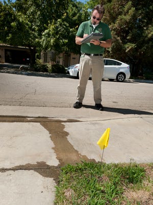Josh Nauman writes a "fix-it" notice for water ordinance violations in the 5000 block of West Feemster Avenue in Visalia on Tuesday, July 1,2014. He is a Water Conservation Education Coordinator for the the City.