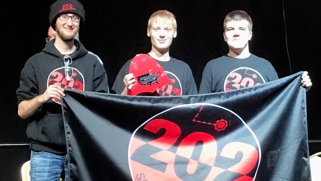 From left, Jacob Delzer, Kelton Lepak and Jordan Sellhausen hold their team banner after their alliance won the CREATE US Open robotics competition on April 7 in Council Bluffs, Iowa.