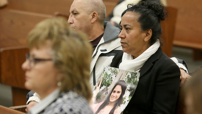 Sitting next to her husband, Angel Hernandez, Carmen Hernandez holds a picture of her daughter Elia during a preliminary hearing for Quin Love in Brownsville, Tenn.