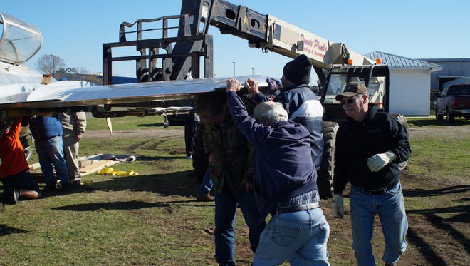 Volunteers at Chennault Aviation & Military Museum work to attach the wings of a Korean War-era Chinese MiG-15 trainer. The museum recently acquired the piece for display and will restore it.