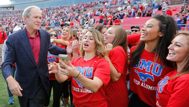 Former President George W. Bush visits with SMU students after flipping the coin on the field before an NCAA college football game between Memphis and SMU in Dallas Saturday.