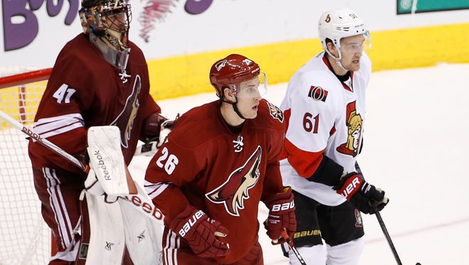 The Arizona Coyotes' Michael Stone (26) and Ottawa Senators' Mark Stone (61), who are brothers, play against each other in front of Coyotes goalie Mike Smith (41) during the third period on Saturday, Jan. 10, 2015, in Glendale.