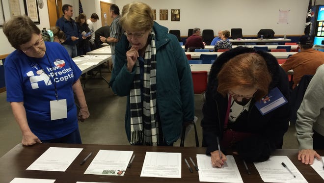Susan Henderson, left, Barbara Pitz and Gloria Erickson sign petitions to get Democratic candidates for senate onto the 2016 ballot at Bettendorf's precinct 23 on caucus night.