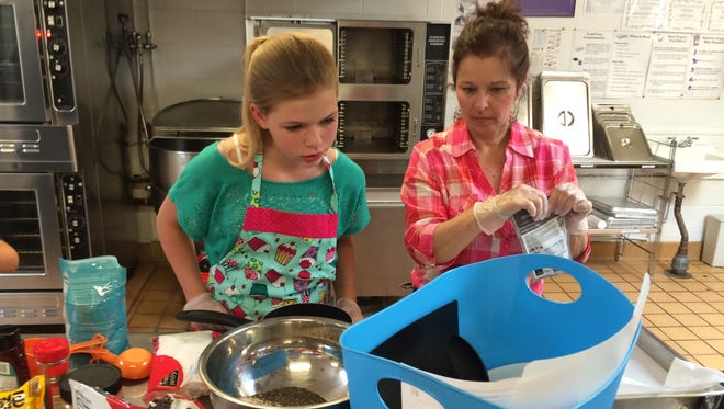 Kaci Swenson of Bethke Elementary looks at her recipe for power bars in the Poudre School District's kids cooking competition.
