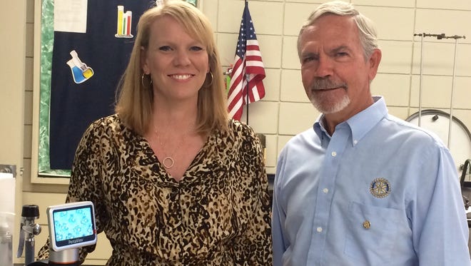 Rapides High science teacher Amy Lewis and Lecompte Rotary Club President Paul St. Romain stand with a new instructor microscope purchased through Rotary grant funds and delivered to the school on Tuesday.