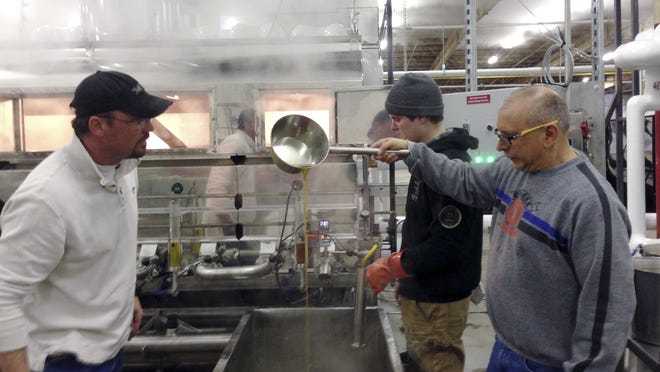 Operations manager Joe Russo, right, checks the density of maple syrup at the Sweetree LLC plant while Scott Boyce, a sales representative for a maple sugar equipment company, looks on in Island Pond. Jon Cox of East Charleston is in the background. Sweetree LLC , an out-of-state company, could become the largest maple syrup producer in North America, tapping into thousands of acres of maple trees in northern Vermont.
