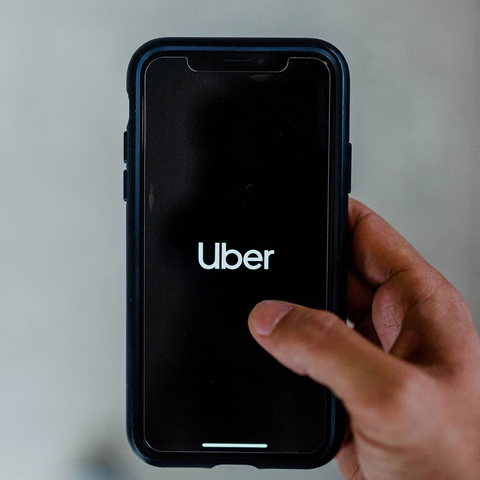 A hand holding a smartphone that displays the Uber