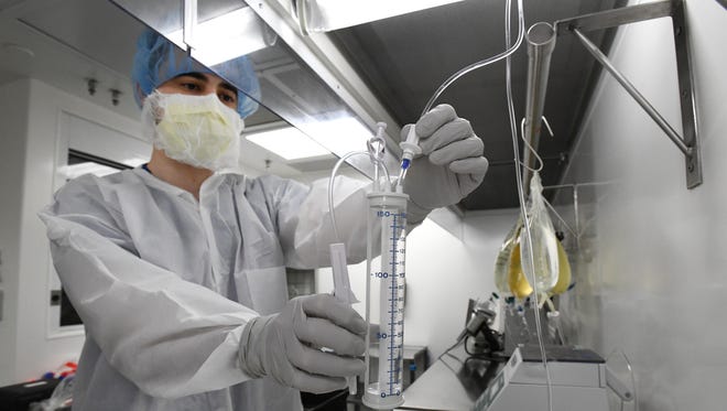 David Melton fills buretrols with normal saline at Beaumont Hospital in Royal Oak on Friday. The hard plastic cylinders containing a reservoir that pharmacists can fill with measured mixtures have been valuable amid IV bag scarcity.
