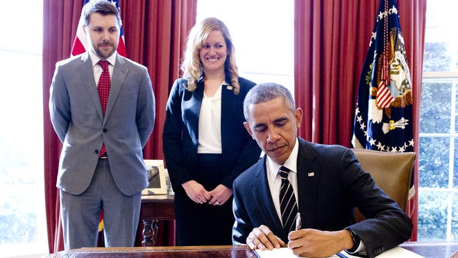 President Obama signs an executive order titled "Planning for Sustainability in the Next Decade" in the Oval Office on March 19. The order will cut the federal government's greenhouse gas emissions by 40% from 2008 levels over the next decade. Standing behind Obama are senior adviser Brian Deese and Christina Goldfuss, managing director of the Council on Environmental Quality.