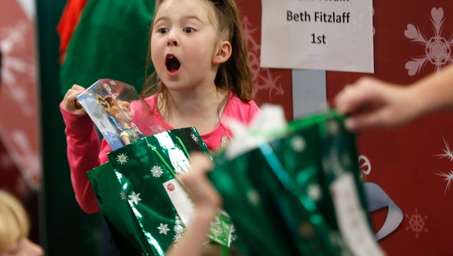 Styler Karrick, a 1st grade student at Mark Twain Elementary School, reacts after opening a present given to her during an assembly Thursday at the school. The James River Church came to the school as a part of their "Season of Giving" program. Church members put on skits, played games with the students and handed out a gift for every child.
