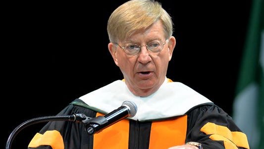 MSU commencement keynote speaker conservative columnist George Will, makes his point by dropping the Comprehensive Immigration Reform Bill on the podium Dec. 13, 2014.