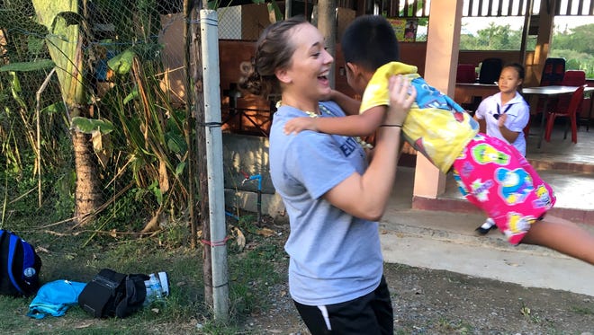Willard's Makenzie Bouse (center) plays with a Thai child at an orphanage during Bouse's visit to Thailand on an Athletes in Action volleyball mission trip.