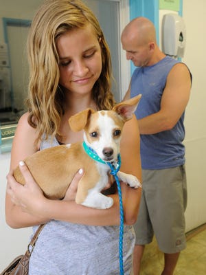 Mya Bagley, 12, holds a puppy she and her father, Brent Bagley of Visalia, at right, adopted Thursday at the Valley Oak SPCA in Visalia. He said he just purchased a house so now they can have a dog.