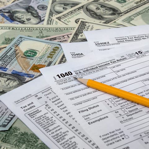 Tax forms, a pencil, and money spread across a fla