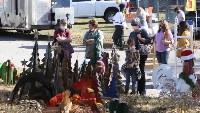 Shoppers look at yard ornaments for sale outside of the River Valley Holiday Market, Saturday, Nov. 7, at Kay Rodgers Park. The shopping event continues Sunday, Nov. 8, noon to 4 p.m., and cost $5 for everyone 12 years old and older. [JAMIE MITCHELL/TIMES RECORD}