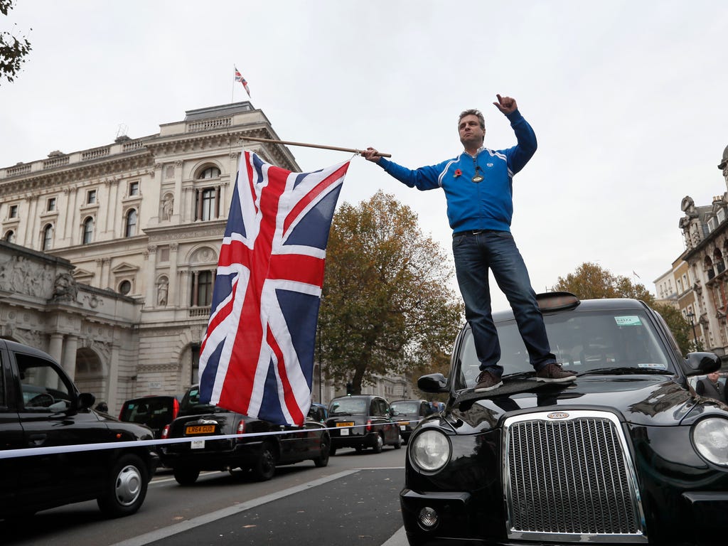 A driver stands on his taxi and waves a Union flag as London's Black Taxi drivers blocked a street near Parliament in London. The drivers are calling for an inquiry into Transport for London over London congestion and air pollution.