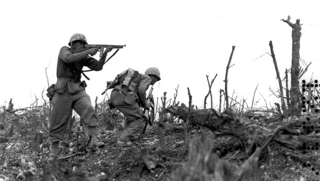 A U.S. Marine of the 1st Division takes aim and fires with his machine gun at a Japanese sniper as his comrade ducks for cover.