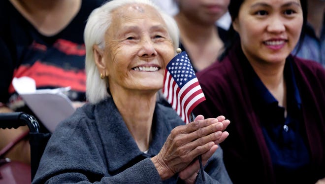 Hong Inh waves an American flag and smiles after taking the oath to become a U.S. citizen at the Los Angeles Convention Center on Aug. 22, 2017.