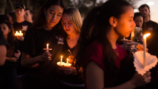 Members of the Stoneman Douglas Eagle Regiment mourn among thousands of other community members during a candlelight vigil at the Pine Trails Park amphitheater Thursday, Feb. 15, 2018, a day after the mass shooting at Marjory Stoneman Douglas High School in Parkland.