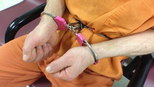 An inmate at the Tippecanoe County jail demonstrated on Monday, May 18, 2015, how handcuffs are attached to a metal waist chain that restricts a prisoner’s ability to move their hands up and down or to the side.