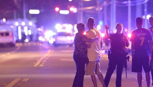Police officers direct family members away from a multiple shooting at a nightclub in Orlando, Fla.