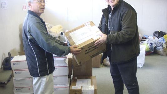 In this photo provided by Joseph Roginski, taken May 13, 2011, Joseph Roginski, right, holds a package in a storeroom of the Misawa City Hall in Japan, where donations of clothing and supplies were being kept for earthquake relief efforts. He says that while the cost of living is higher in Japan, access to health care is not. “Things are very expensive here. It is impossible to live off Social Security alone,” said Roginski, who was stationed in Japan in 1968. “But health insurance is a major factor in staying here.” The former military language and intelligence specialist said he pays $350 annually to be part of Japan’s national health insurance. His policy covers 70 percent of his costs. The rest is covered by a secondary insurance program for retired military personnel.
