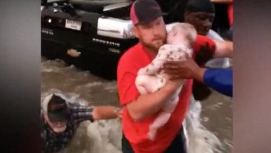 A Texas man holds a baby pulled from a vehicle on Saturday.