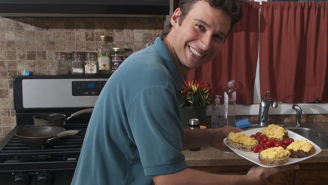 Stilian Kirov, music director with Symphony in C, shows off his scramble egg sandwich dish at his Cherry Hill home.
