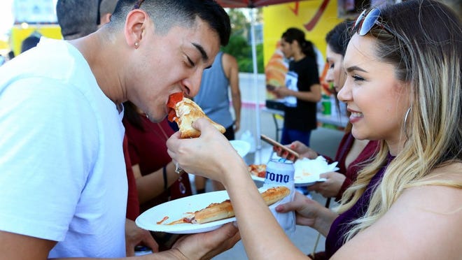 Jacob Saldana gets help eating a slice of pizza from Clarissa Saldana during the first day of the Fiesta de la Flor festival Friday, May 6, 2016, in Corpus Christi.