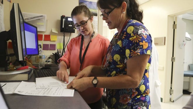 Katelyn Sharp, left, a family nurse practitioner fellow with the Shasta Community Health Center's Nurse Practitioner and Physicians Assistant Fellowship Program, goes over what immunizations patient Thomas Secrest, 1, needs with Medical Assistant Lindy Kolar at the center.