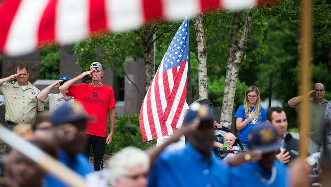Audience members salute and hold hands over their hearts during the national anthem Monday during the Memorial Day Ceremony in Pack Square Park.