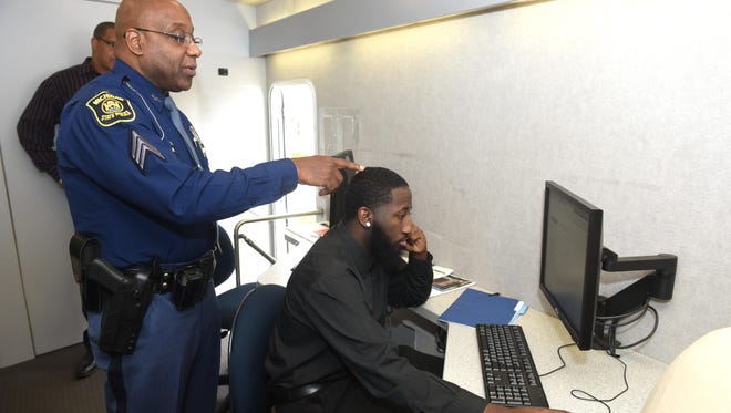 Michigan State Police Sgt. Dwanye Gill, left, assists Aaron Stephens, of Detroit as he prepares the civil service test during Michigan State Police’s minority recruiting seminar last month at Second Ebenezer Church in Detroit.